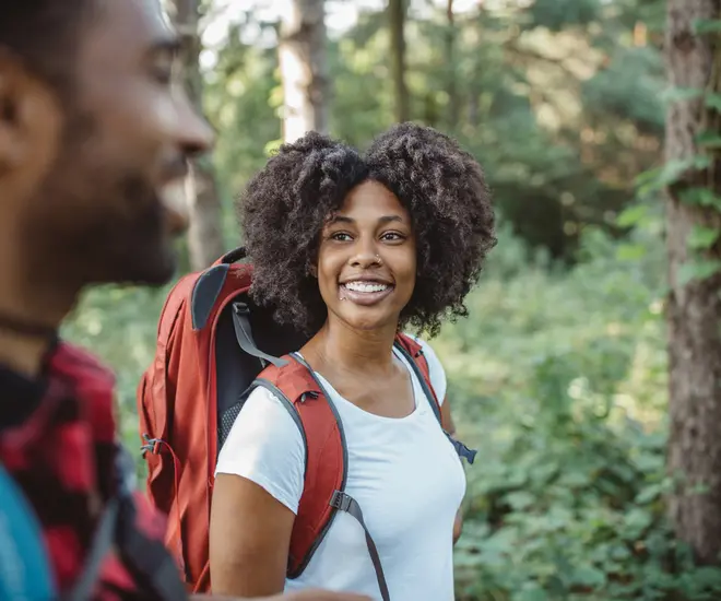 Black woman hiking with backpack and male companion