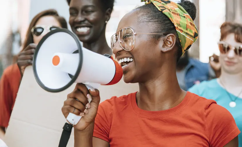 A young woman advocates while holding a megaphone. Learn how to support advocates like her in this advocacy software guide.