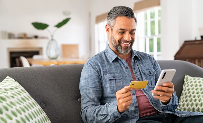 Thanks to these last-minute GivingTuesday tips, this man siting on his couch makes a donation to a nonprofit using his phone.