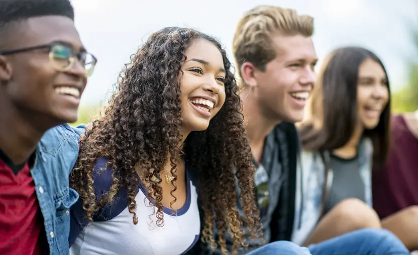 This guide walks through effective ways to engage younger donors, such as these four young people sitting and smiling side by side.
