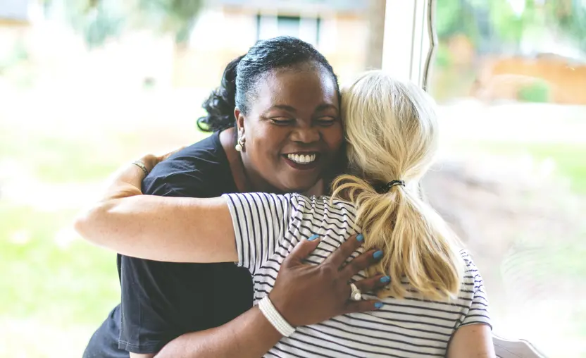 A nonprofit representative greets a donor with a hug.