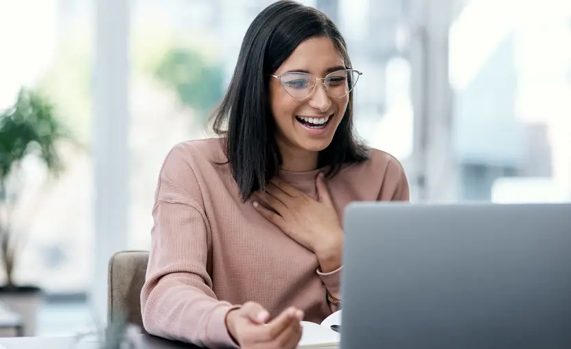 Shot of a young woman using a laptop and looking surprised while working on hosting an auction online. Learn how to host an auction in this guide.