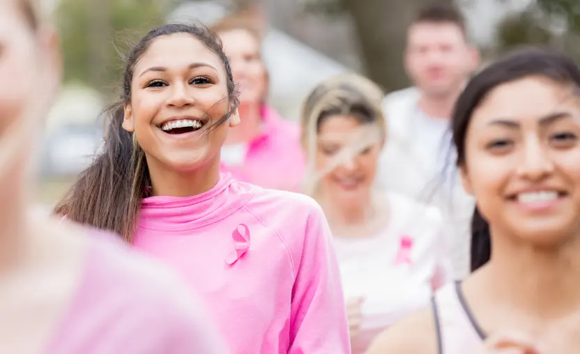 women smile while running in support of breast cancer research. They are cultivating giving tuesday success by wearing pink clothing with breast cancer awareness ribbons.