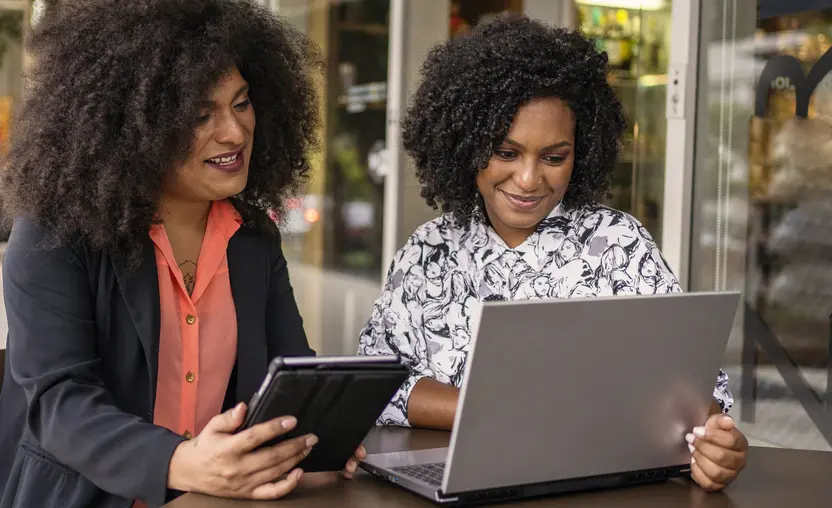 Two women look at laptop and tablet screens as they implement marketing automation for nonprofits.