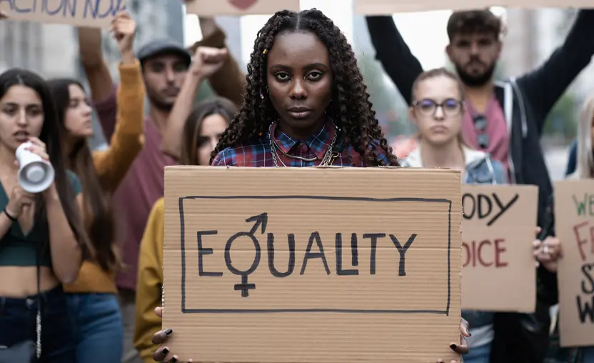 A protestor stands in a crowd holding an equality sign as part of the fight for reproductive justice. 
