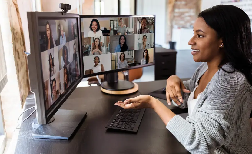 A woman at her computer discusses virtual fundraising ideas with a group of people in a video conference.