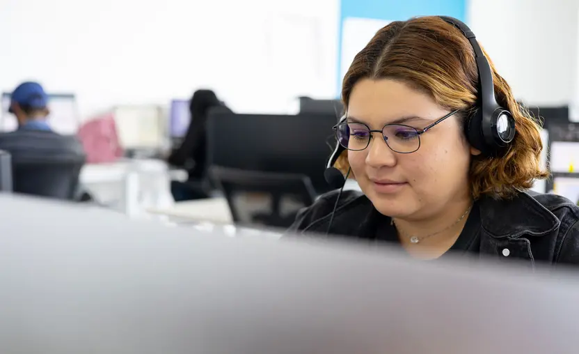 Employee sitting at desk wearing headphones while doing computer work