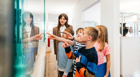 A group of young kids looking at various objects and images on display while on a field trip to a museum.