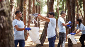 A group of coworkers wearing matching blue shirts participate in a community cleanup event, demonstrating the result of encouraging employee giving. 