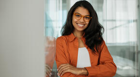 Portrait of smiling business woman wearing stylish eyeglasses looking at camera standing in modern office.