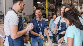 A diverse group of volunteers enjoys working together to assemble meals for the food bank event.