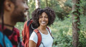 Black woman hiking with backpack and male companion