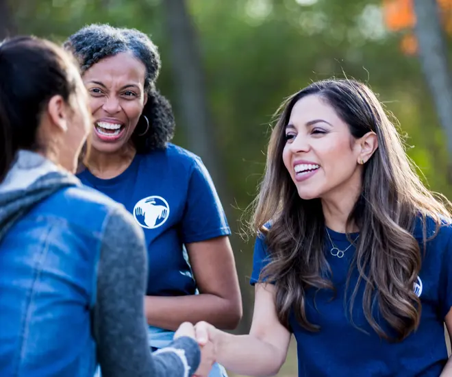 As the adult female nonprofit smiles, she shakes hands with a donor before the park cleanup begins. Learn how to build donor relationships like this in this donor appreciation guide.