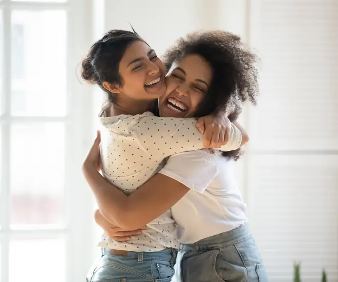 Two young women hugging indoors