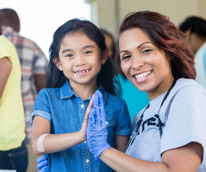 Young patient and female doctor high five during a free community health fair.