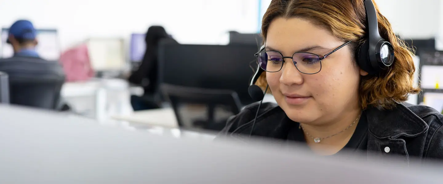 Employee sitting at desk wearing headphones while doing computer work