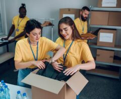Volunteers wearing matching yellow shirts sort donated clothing and supplies in a community organization’s workspace, illustrating how structured volunteer activities and accurate tracking help nonprofits stay organized and amplify their impact.