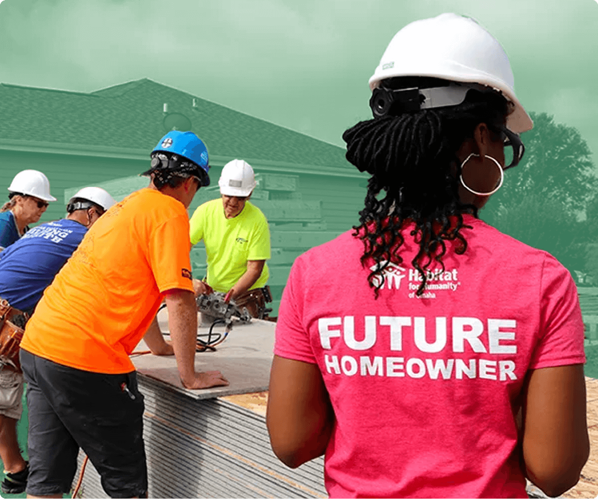 Woman wearing a 'Future Homeowner' shirt and hard hat at a construction site with Habitat for Humanity volunteers.