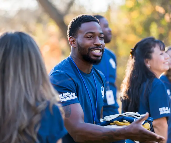 Charity event organizer greets a peer during a community cleanup day.