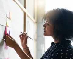 woman looking at post it notes on a whiteboard.