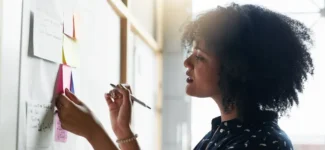 woman looking at post it notes on a whiteboard.