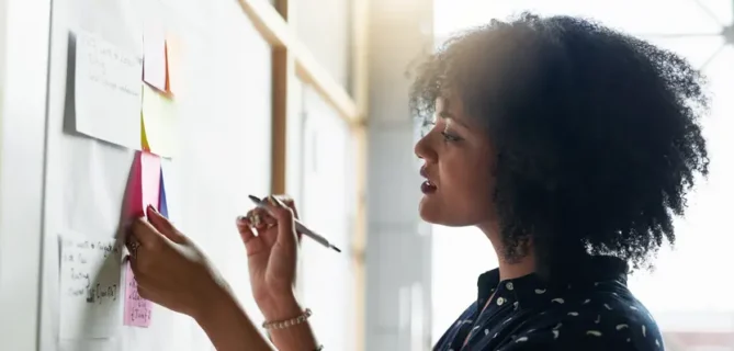 woman looking at post it notes on a whiteboard.