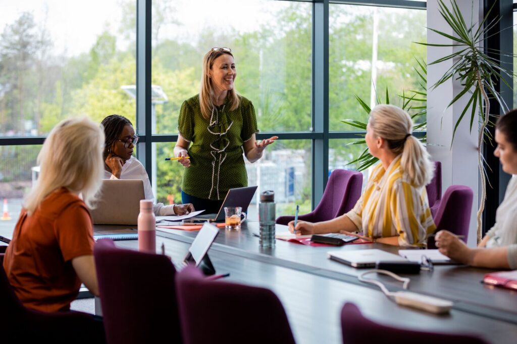 A wide-angle view of a group of a woman getting together for a business meeting in their place of work
