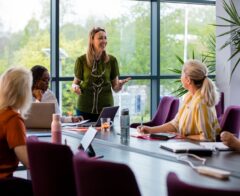 A wide-angle view of a group of a woman getting together for a business meeting in their place of work