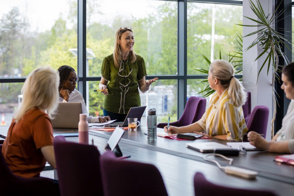 A wide-angle view of a group of a woman getting together for a business meeting in their place of work