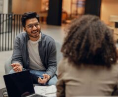 Man smiling and talking with a woman in a modern office setting.