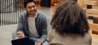 Man smiling and talking with a woman in a modern office setting.