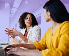 Two women sitting at a table working together with a laptop