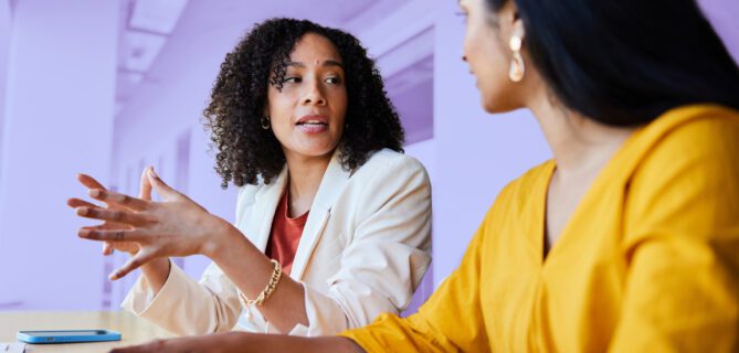 Two women sitting at a table working together with a laptop