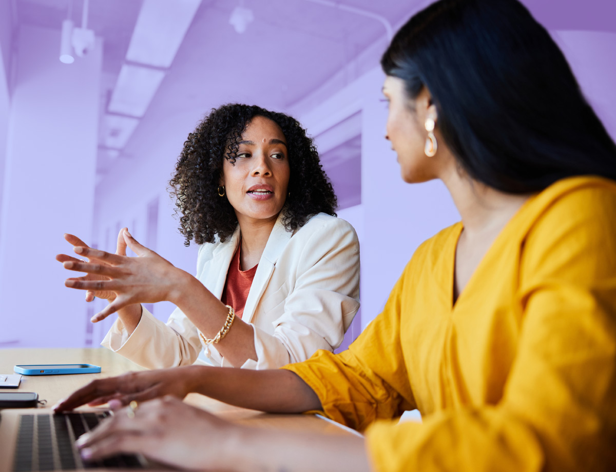 Two women sitting at a table working together with a laptop