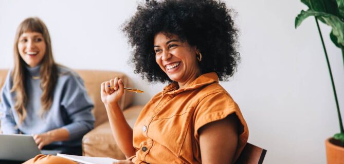 Businesswoman smiling happily while sitting in a meeting with her colleague.