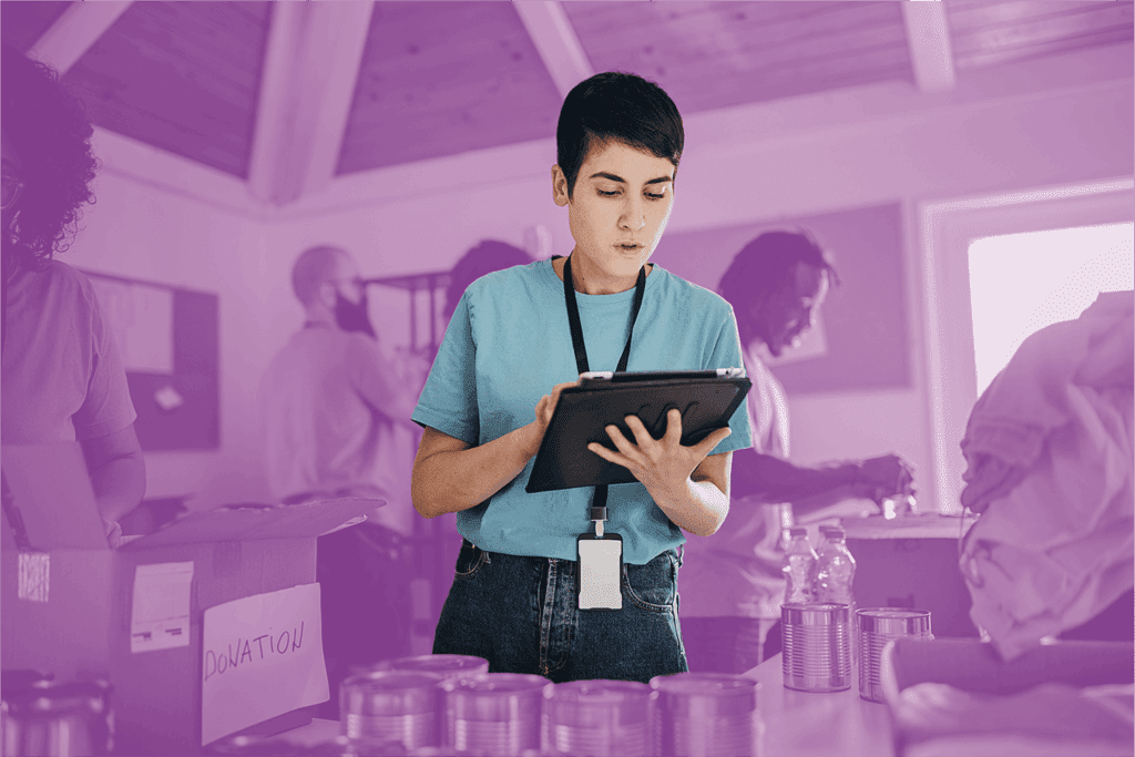 Volunteer using a digital tablet to manage donations at a food and supplies drive.