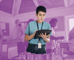 Volunteer using a digital tablet to manage donations at a food and supplies drive.