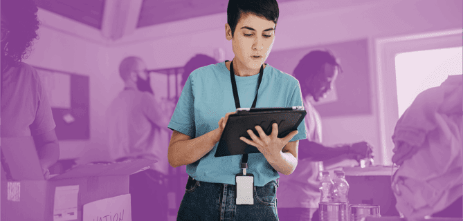 Volunteer using a digital tablet to manage donations at a food and supplies drive.