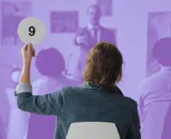 Stock photo of a crowded room with an auction occurring.