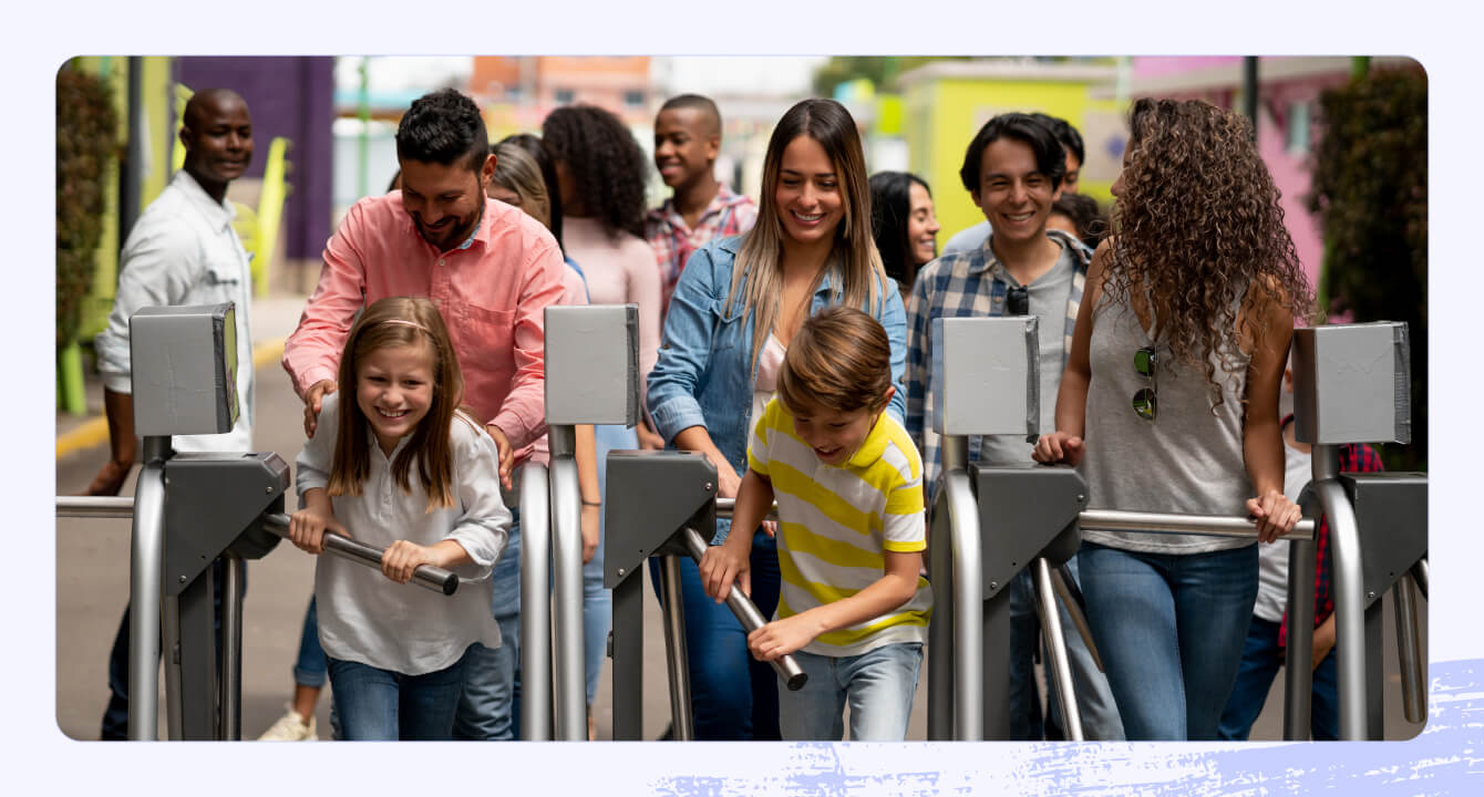 A family entering a theme park through turnstiles.