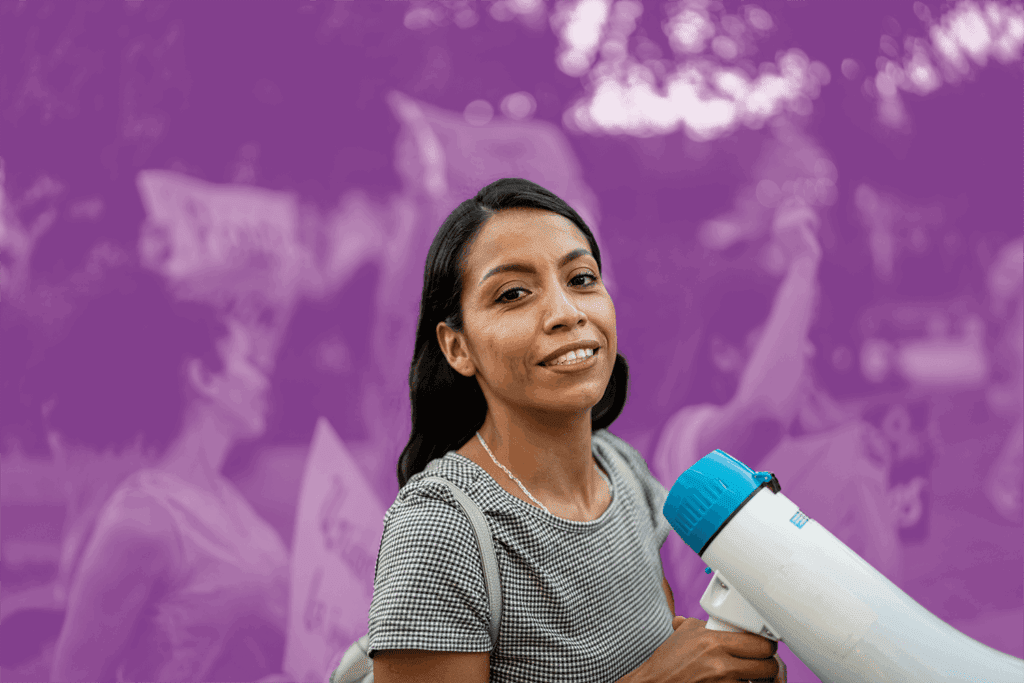 Woman holding a megaphone and smiling at a rally or protest event.