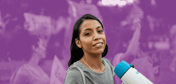 Woman holding a megaphone and smiling at a rally or protest event.