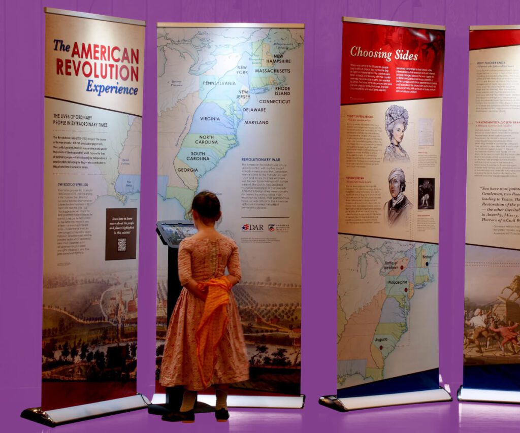 Young girl reading exhibit panels about the American Revolution.