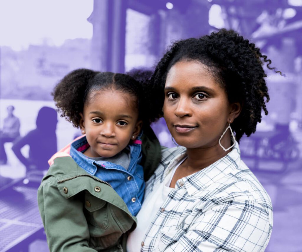 Mother holding her young daughter at a public park.