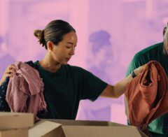 Two volunteers folding clothing donations.
