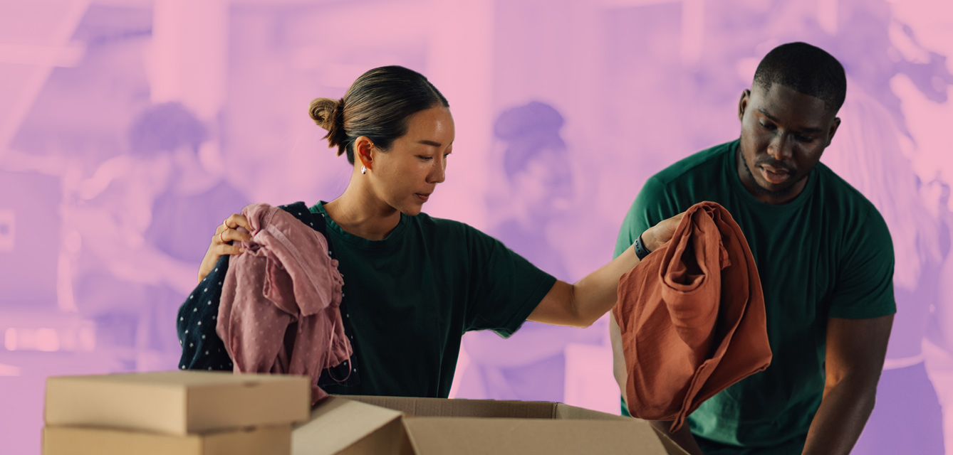 Two volunteers folding clothing donations.