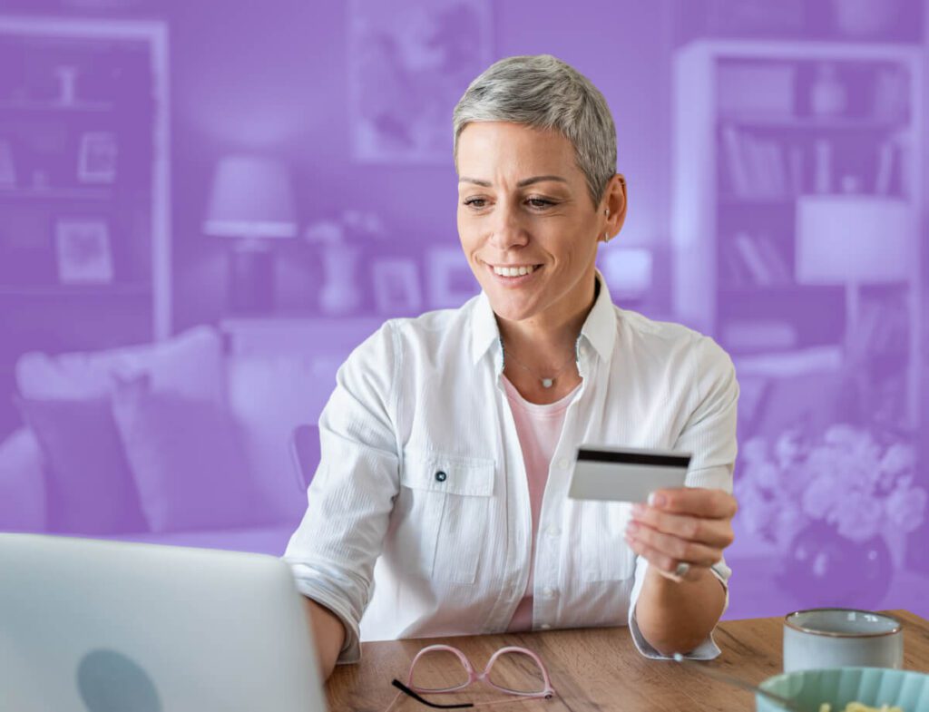 A woman working on a laptop while holding a debit card.