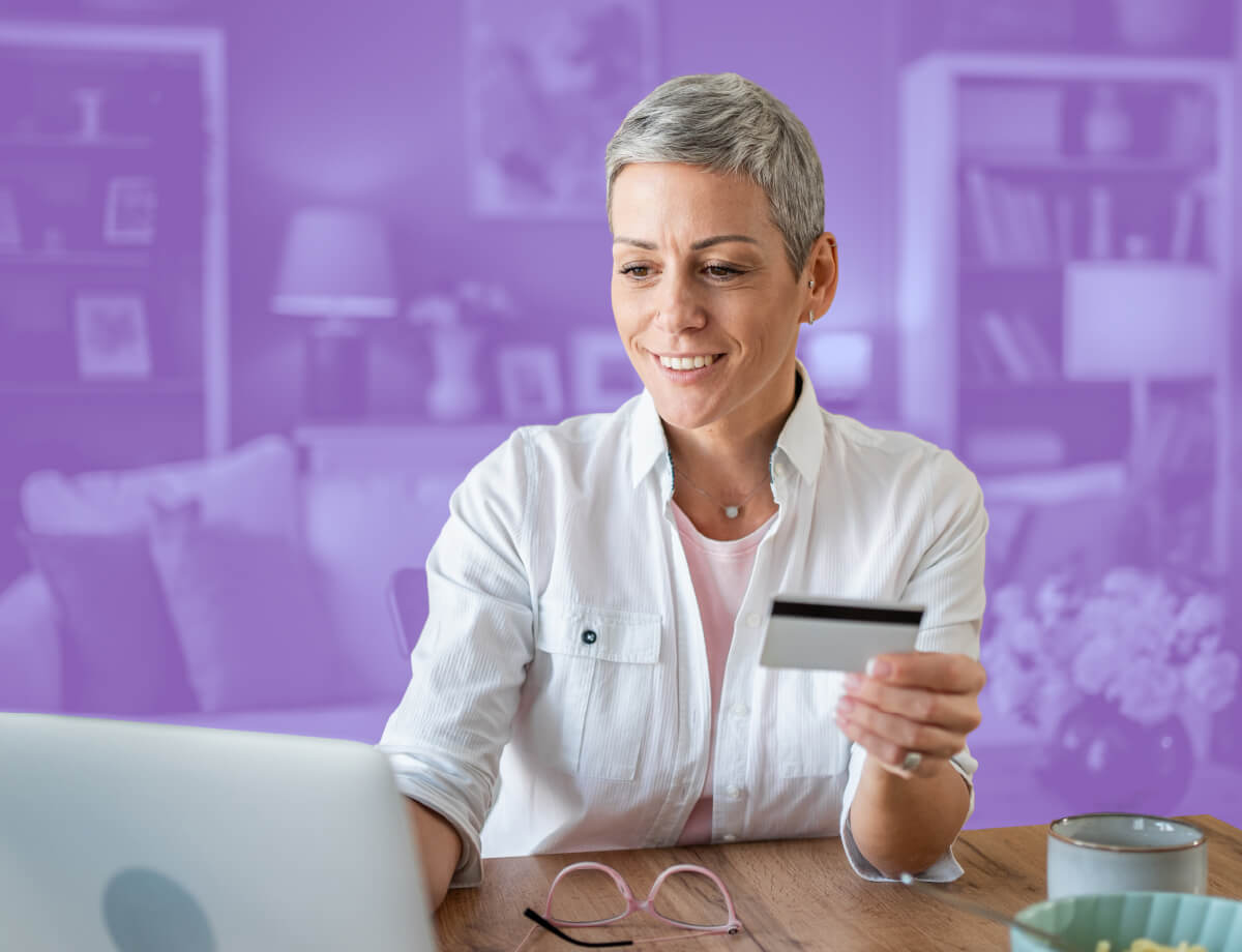 A woman working on a laptop while holding a debit card.
