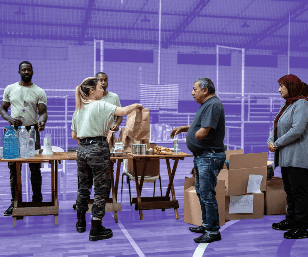 Volunteers distribute food and supplies to community members inside a gymnasium. People stand by donation boxes and tables with bottled water and packaged meals. The background is tinted purple to match Bonterra’s brand style.