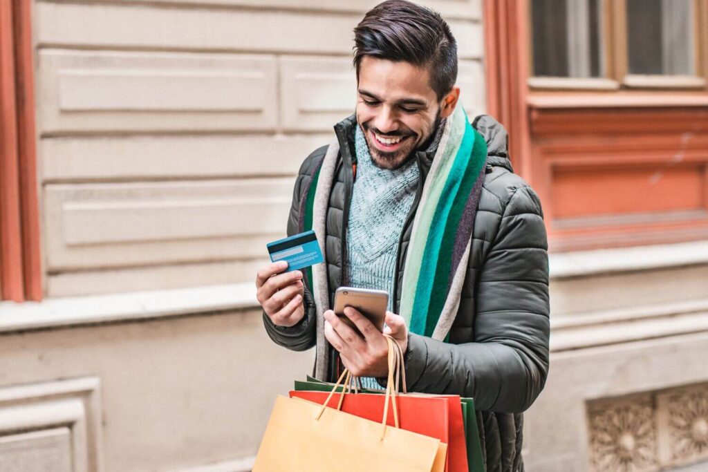 A smiling man holding a credit card and phone, symbolizing generosity and the ease of giving—ideal for promoting effective year-end donation appeals.